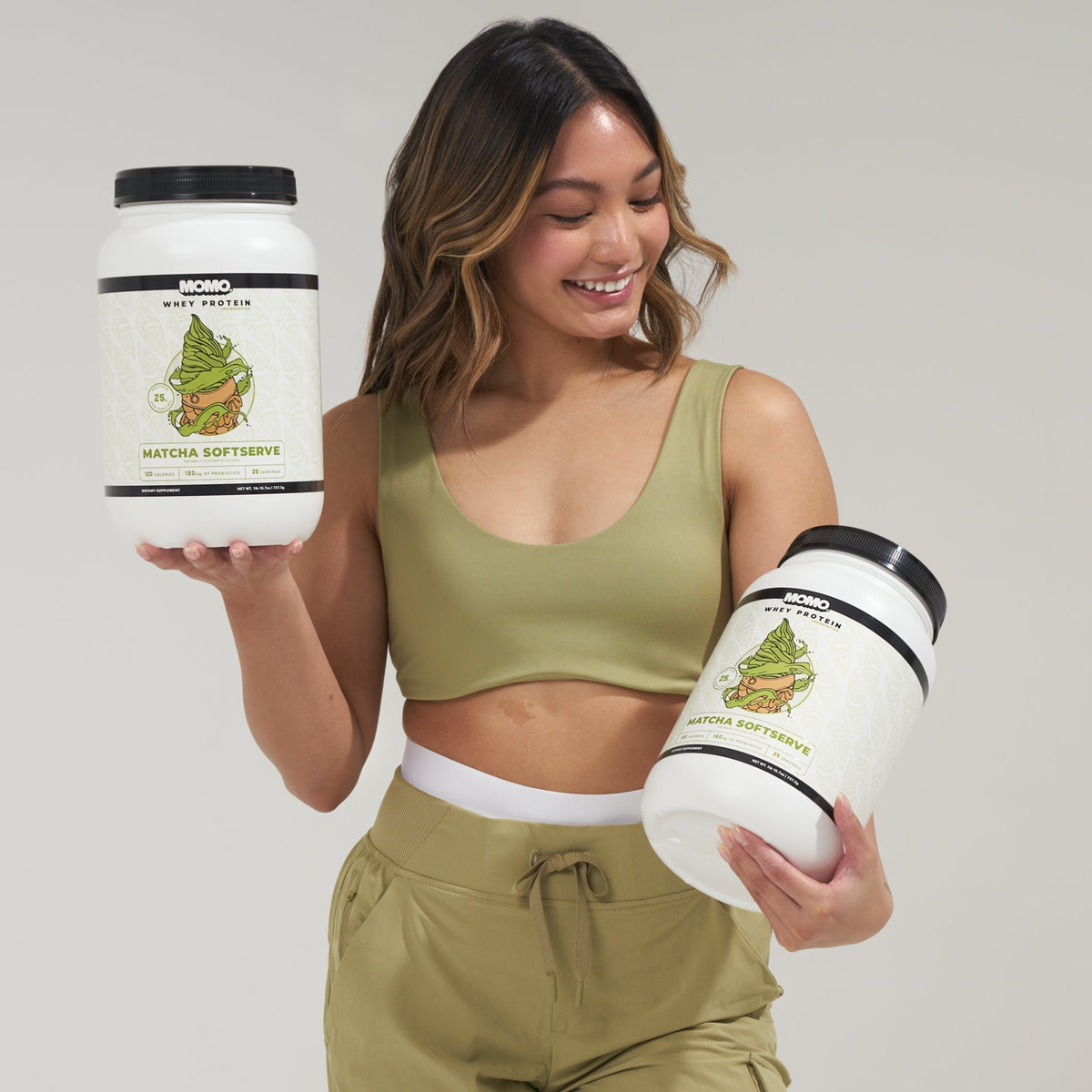 Smiling woman holding two tubs of MOMO whey protein