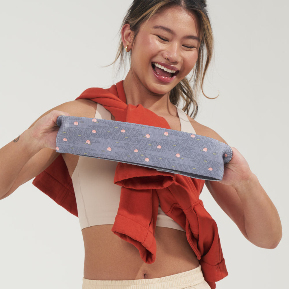 Smiling woman stretching a MOMO Peach Puddles glute band