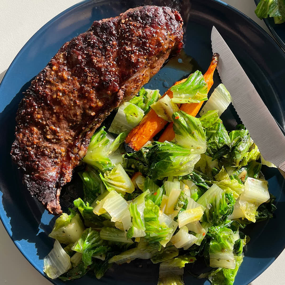 a delicious plate of green leafy veggies and a big perfectly seared steak, a natural source of high protein