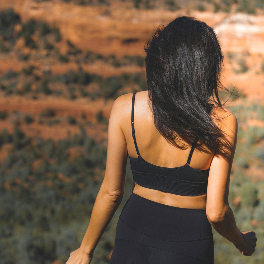 Woman with long dark hair walking outdoors, seen from behind