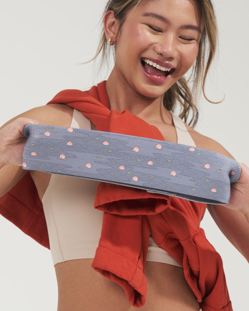 Asian girl stretching a cute fabric booty band with a cute Japanese river and peach design