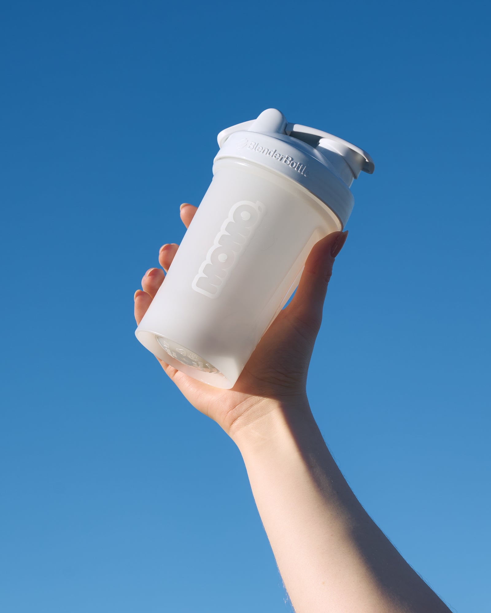 MOMO 20oz White BlenderBottle with wire whisk held towards the sky