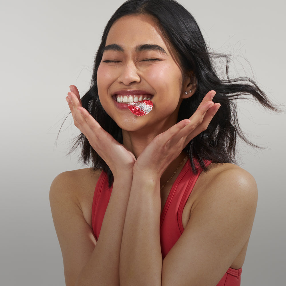 Asian girl smiling while biting on a yakult lid